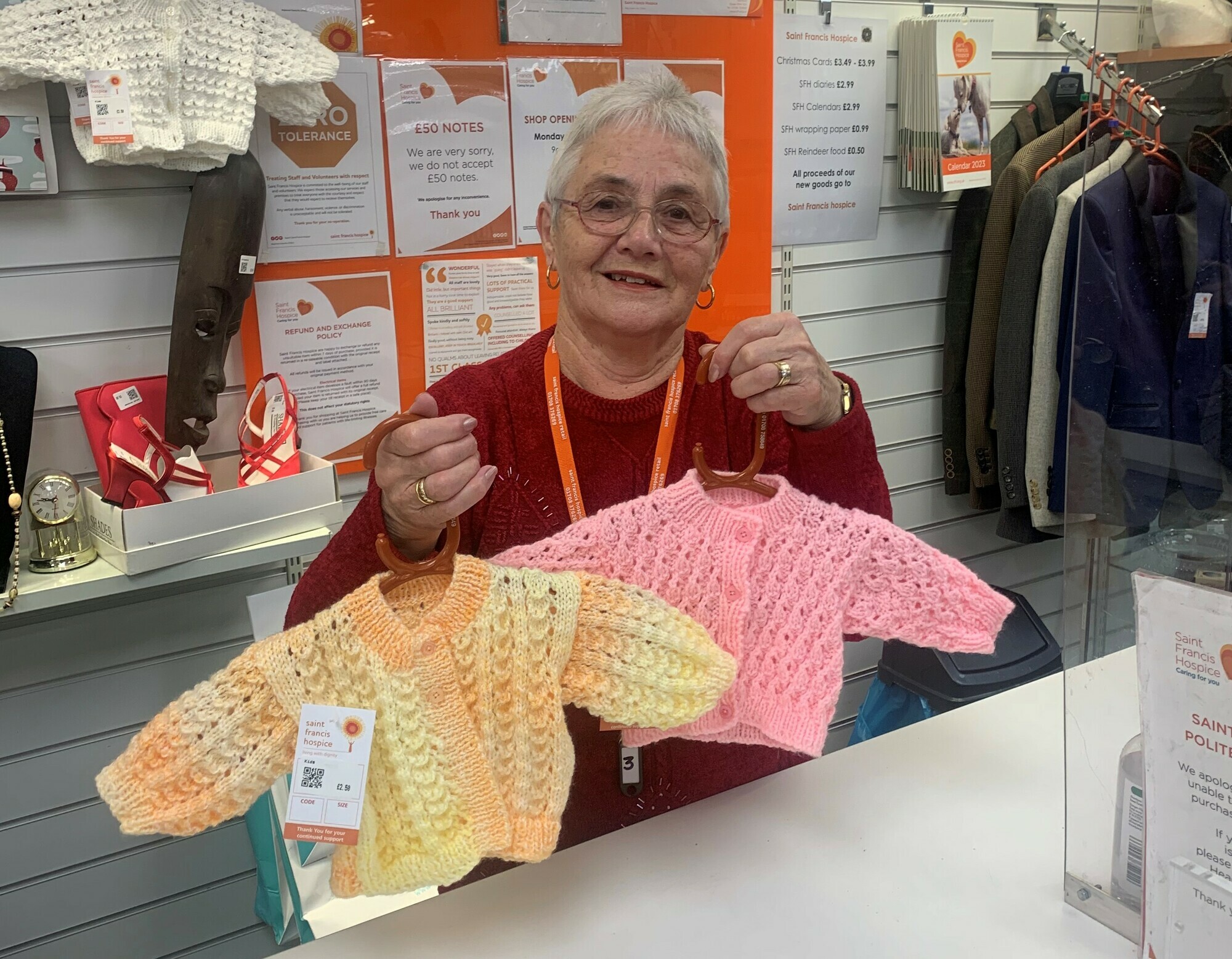 Peggy holding knitted baby cardigans she has made crop