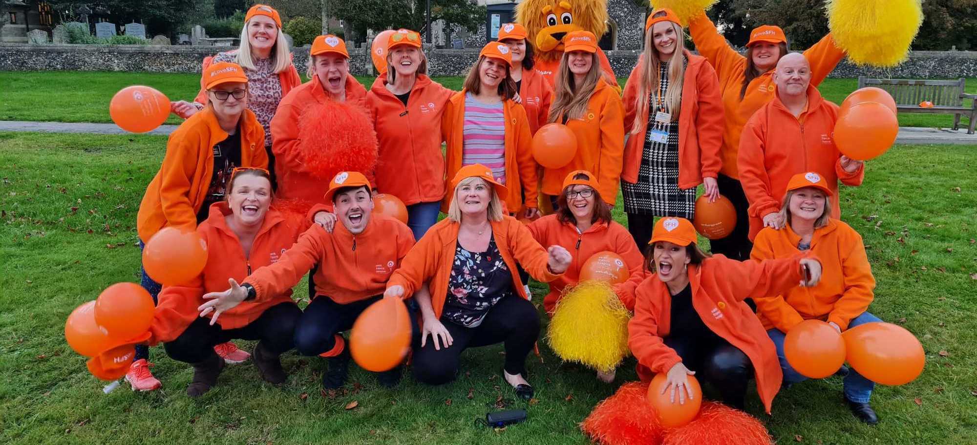 Fundraising team in orange on the green - Jerusalema dance practice 5 (cropped)