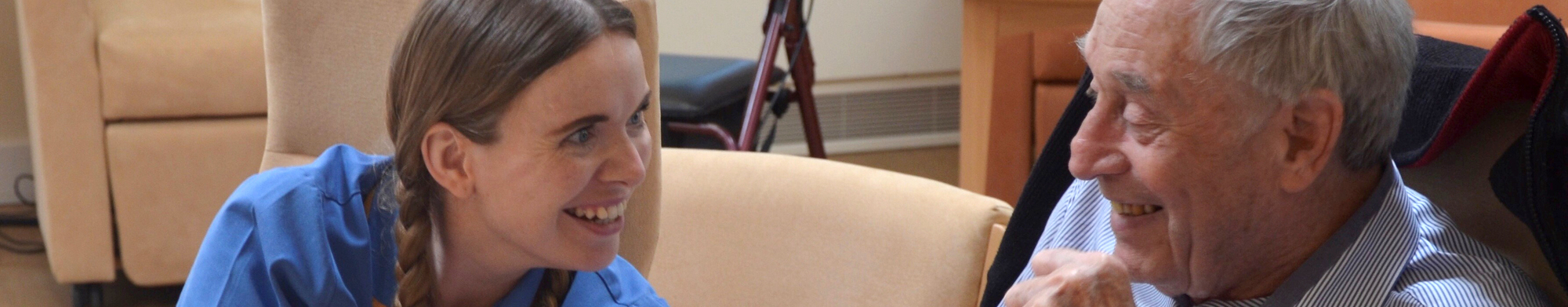 Healthcare Assistant Aimee Mabbort laughing with a patient (cropped)