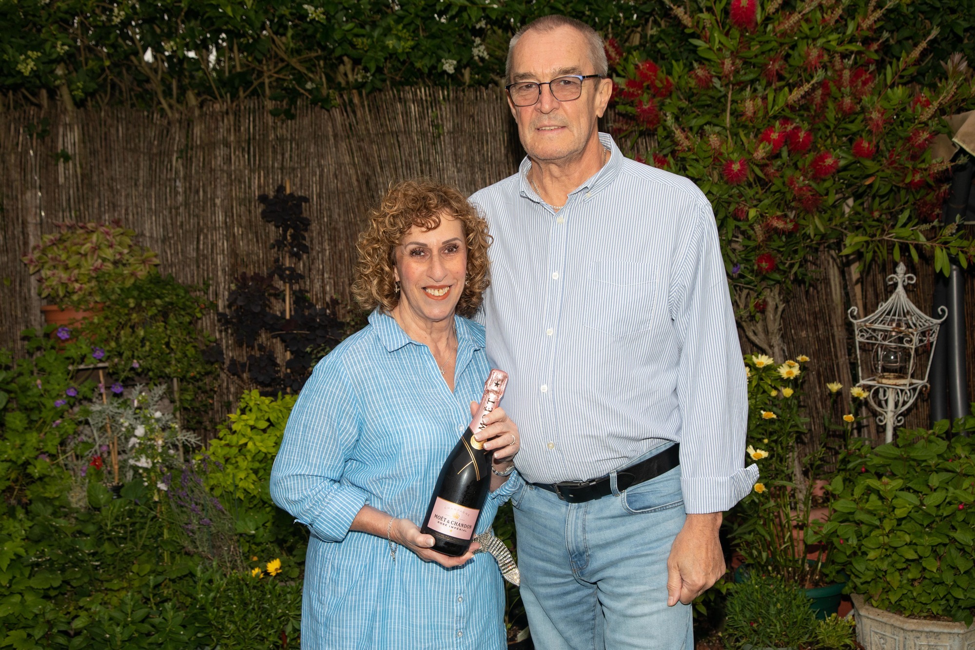 Amanda and John celebrate with bottle of bubbly-min