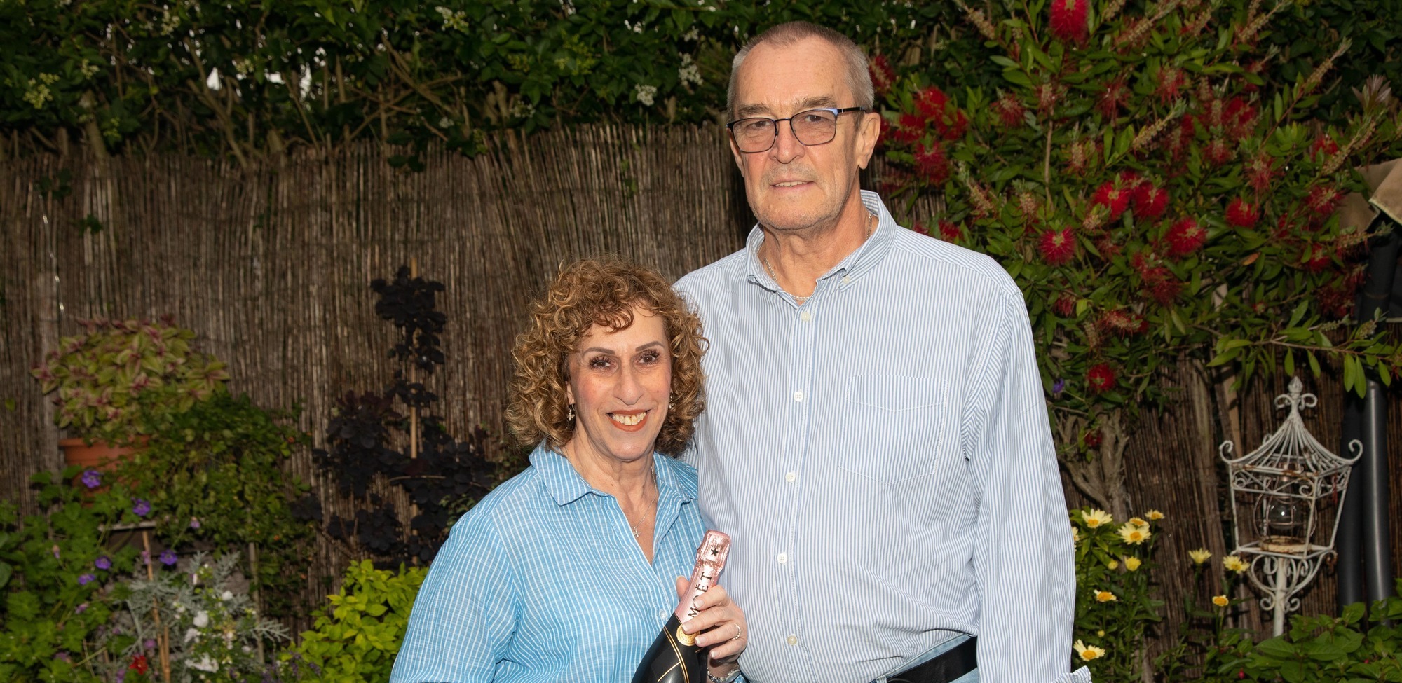 Amanda and John celebrate with bottle of bubbly-min (cropped)