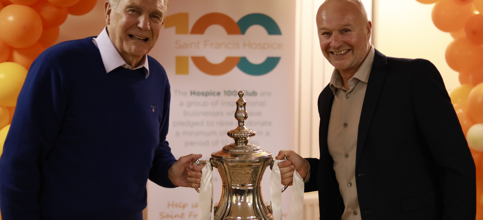 Sir Trevor Brooking with Steve Drew of Drew and Son Independent Family Funeral Directors holding a r